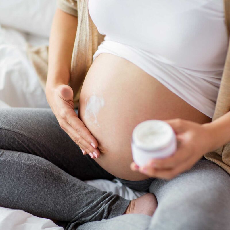 Woman applying stretch mark cream during pregnancy