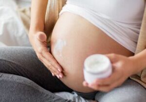 Woman applying stretch mark cream during pregnancy